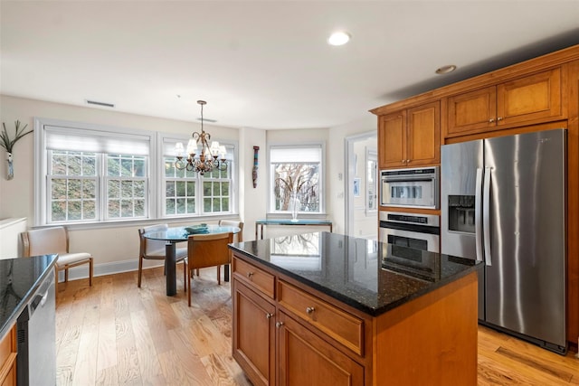 kitchen with decorative light fixtures, a center island, light hardwood / wood-style flooring, dark stone countertops, and stainless steel appliances