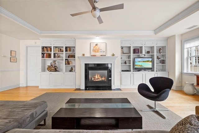 living room featuring light hardwood / wood-style flooring, ornamental molding, and a raised ceiling