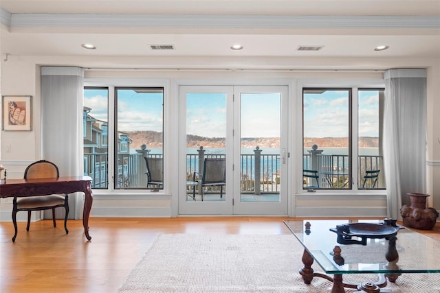 doorway to outside featuring crown molding, a water view, and light hardwood / wood-style floors