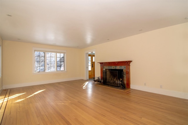 unfurnished living room featuring a tiled fireplace and light wood-type flooring