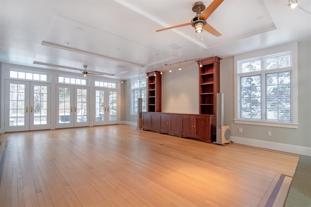 unfurnished living room featuring french doors, ceiling fan, a raised ceiling, and light hardwood / wood-style floors