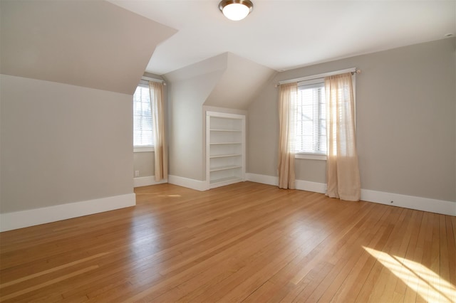 bonus room featuring lofted ceiling, a healthy amount of sunlight, light hardwood / wood-style flooring, and built in shelves