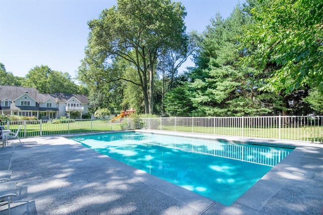 view of swimming pool featuring a playground and a lawn