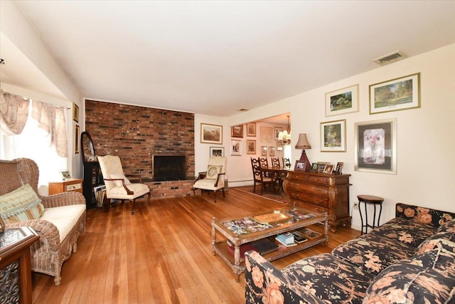 living room featuring a baseboard radiator, light hardwood / wood-style floors, and a brick fireplace