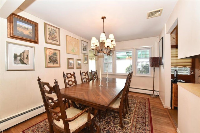 dining room with baseboard heating, hardwood / wood-style floors, and a notable chandelier