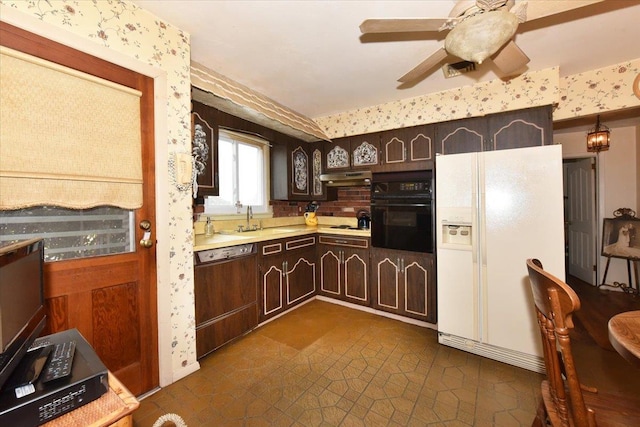 kitchen featuring dishwasher, white refrigerator with ice dispenser, dark brown cabinets, sink, and black oven