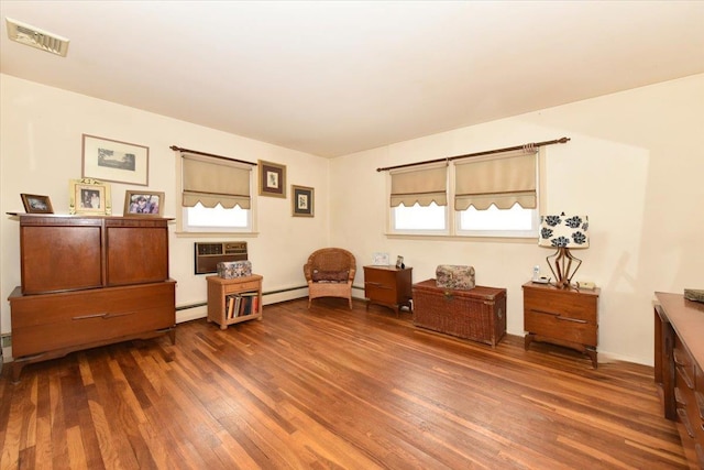 sitting room featuring a wall mounted air conditioner, baseboard heating, and dark wood-type flooring