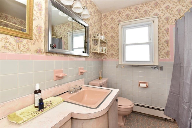 bathroom with toilet, tile walls, a baseboard radiator, sink, and tile patterned floors