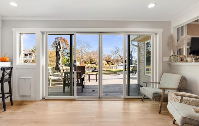 doorway to outside featuring crown molding and light hardwood / wood-style floors