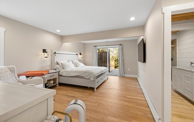 bedroom featuring access to exterior, light hardwood / wood-style flooring, and sink