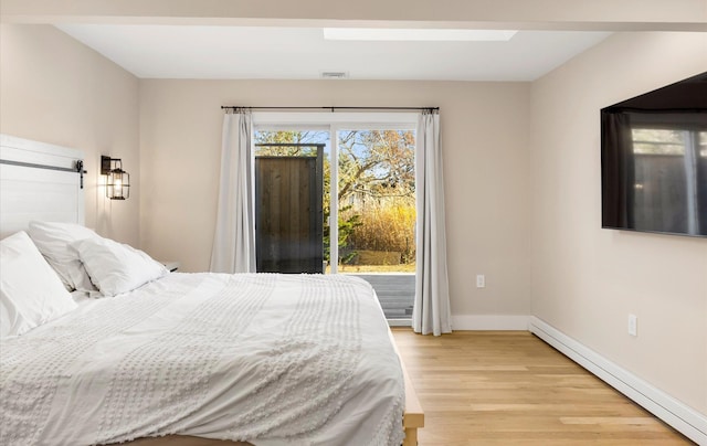 bedroom with a baseboard radiator, multiple windows, and light hardwood / wood-style floors