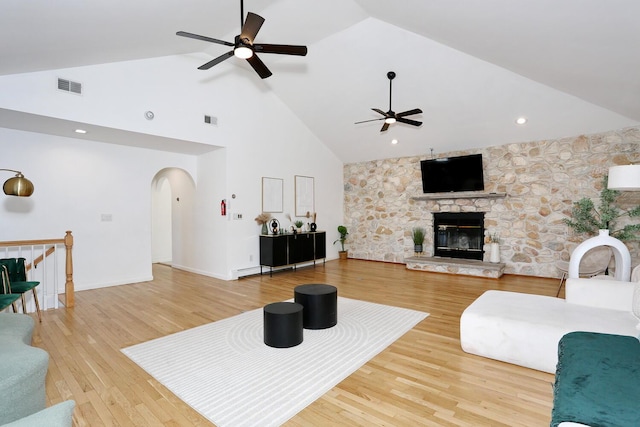 living room featuring ceiling fan, wood-type flooring, a fireplace, and high vaulted ceiling