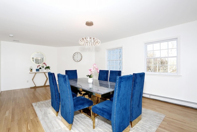 dining space featuring a baseboard radiator and light wood-type flooring