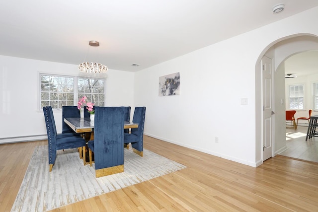 dining room with an inviting chandelier, a baseboard heating unit, and wood-type flooring