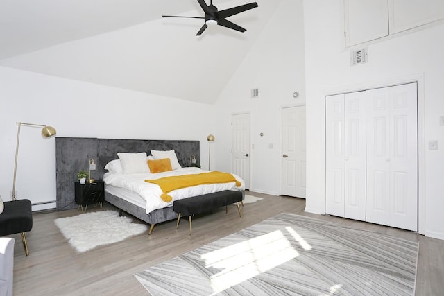 bedroom with a baseboard heating unit, high vaulted ceiling, light wood-type flooring, and ceiling fan