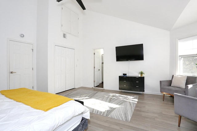 bedroom featuring wood-type flooring, ceiling fan, high vaulted ceiling, and a closet