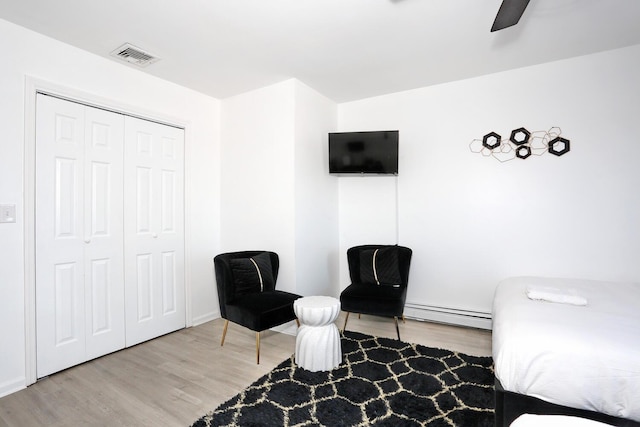 bedroom featuring wood-type flooring, a baseboard radiator, a closet, and ceiling fan