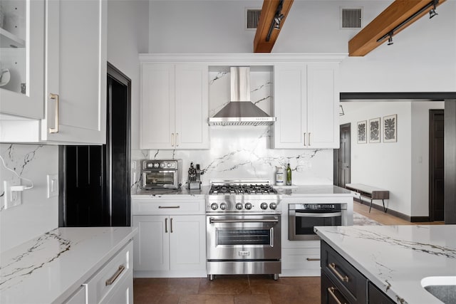 kitchen featuring white cabinets, stainless steel appliances, light stone countertops, and wall chimney exhaust hood