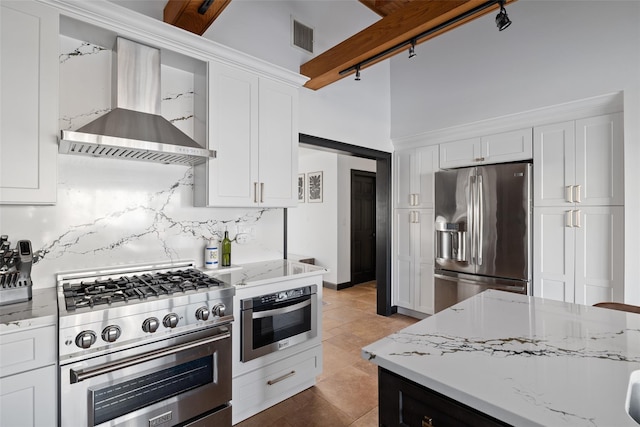 kitchen with white cabinets, decorative backsplash, wall chimney range hood, and appliances with stainless steel finishes