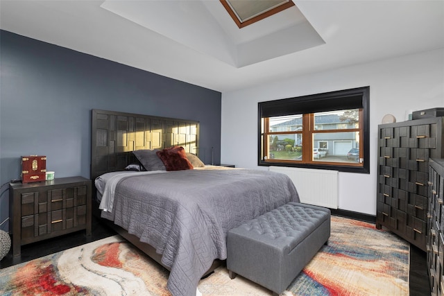 bedroom featuring radiator heating unit, vaulted ceiling, and a raised ceiling