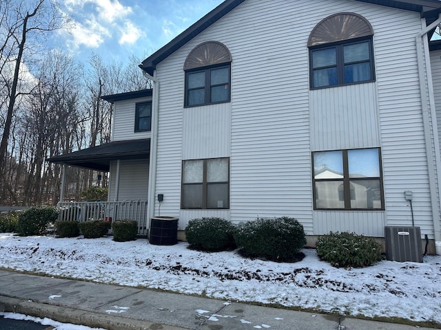 snow covered property with covered porch and central air condition unit