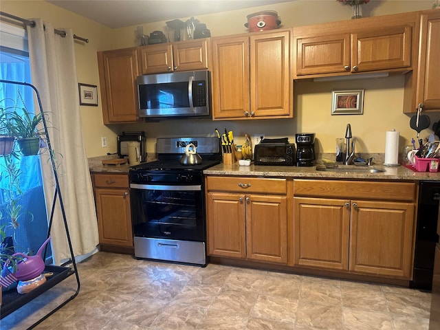 kitchen featuring light stone counters, stainless steel appliances, and sink