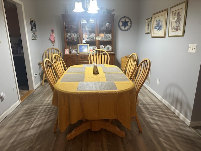 dining area with baseboards and dark wood-type flooring