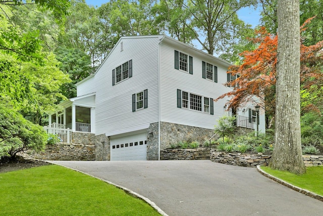 view of front of property with a garage, a sunroom, and a front yard