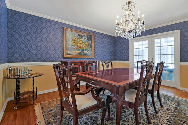 dining room with hardwood / wood-style flooring, ornamental molding, and french doors