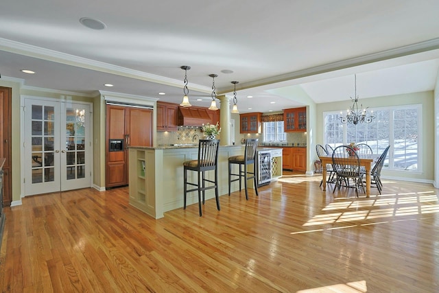 kitchen featuring decorative light fixtures, light hardwood / wood-style floors, and french doors