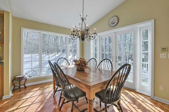 dining area featuring lofted ceiling, a notable chandelier, and light hardwood / wood-style flooring