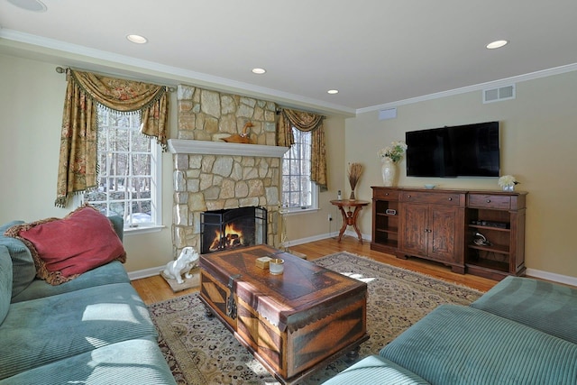 living room with hardwood / wood-style flooring, crown molding, and a stone fireplace