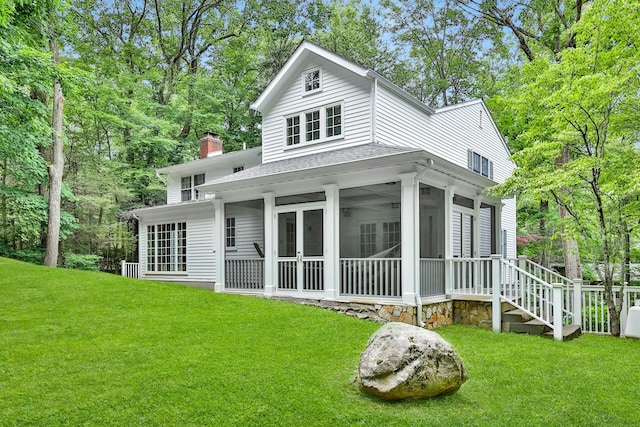 rear view of house with a sunroom and a yard