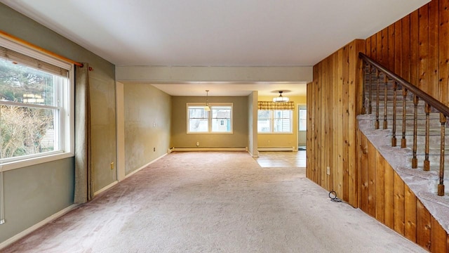 spare room with a baseboard radiator, carpet floors, and wood walls