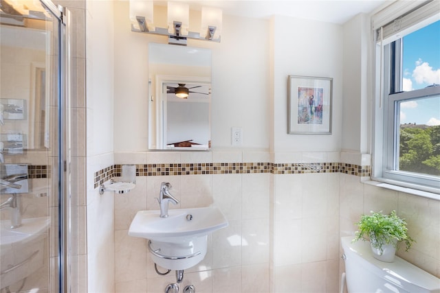 bathroom featuring sink, toilet, a shower with door, and tile walls