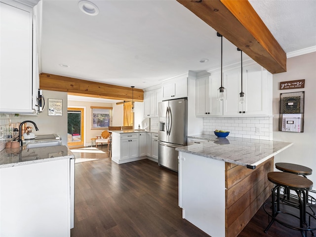 kitchen featuring kitchen peninsula, stainless steel refrigerator with ice dispenser, sink, and hanging light fixtures