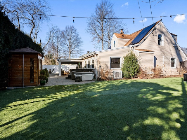 back of property with ac unit, a shed, a lawn, a hot tub, and a patio area