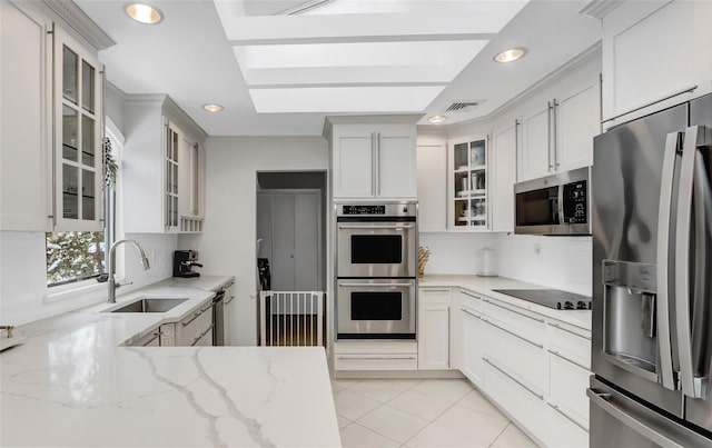 kitchen with sink, stainless steel appliances, light stone counters, white cabinets, and light tile patterned flooring