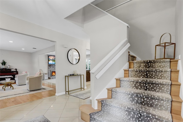 stairway with tile patterned flooring and a large fireplace