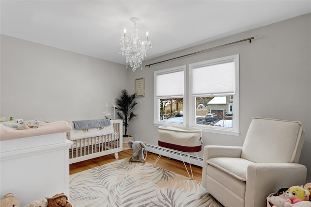 bedroom featuring wood-type flooring, a crib, a chandelier, and a baseboard radiator