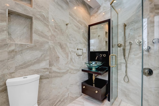 bathroom featuring a shower with door, sink, tile walls, and toilet