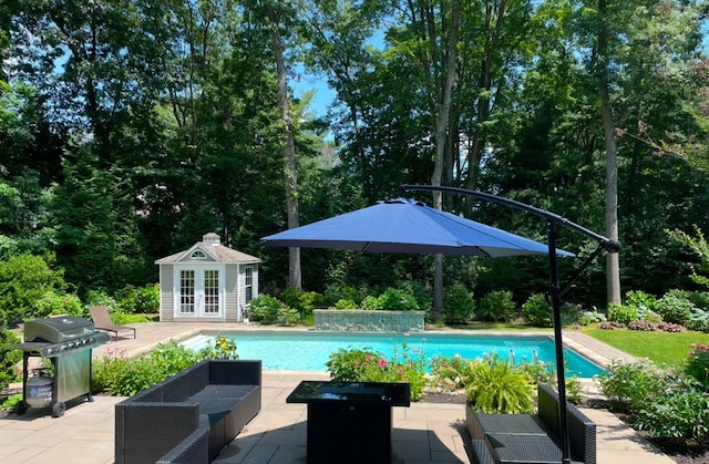 view of pool with grilling area, an outdoor structure, and a patio