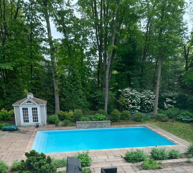 view of pool with an outbuilding, central AC unit, and a patio area