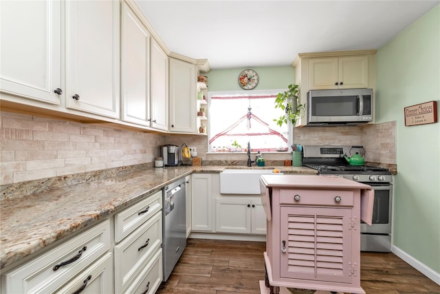 kitchen featuring appliances with stainless steel finishes, decorative backsplash, sink, light stone counters, and dark hardwood / wood-style floors