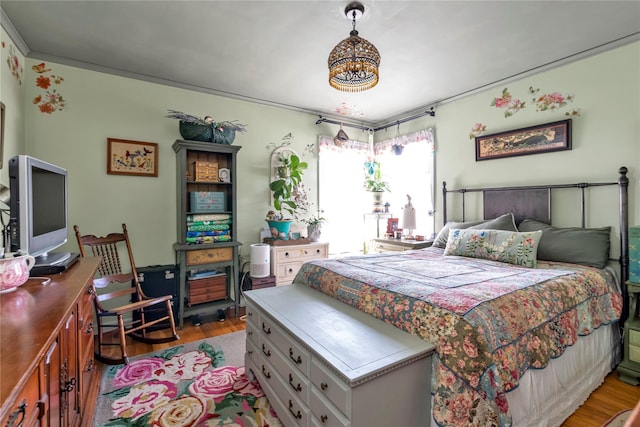 bedroom featuring hardwood / wood-style floors, crown molding, and a notable chandelier