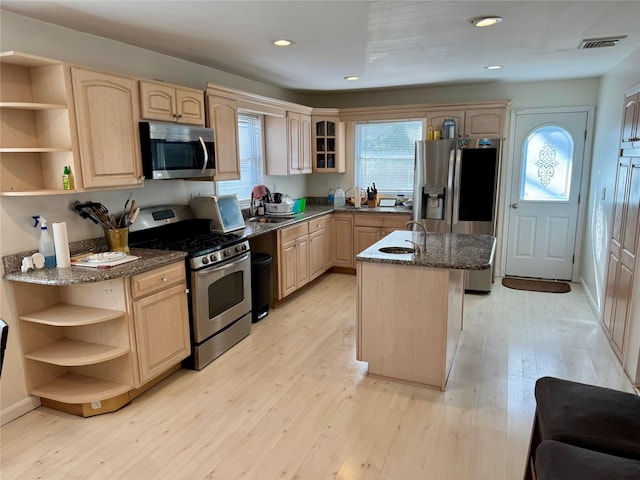 kitchen featuring appliances with stainless steel finishes, light brown cabinetry, visible vents, and open shelves