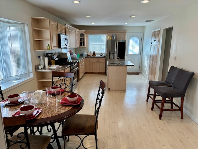 kitchen with light wood finished floors, open shelves, visible vents, appliances with stainless steel finishes, and a kitchen island