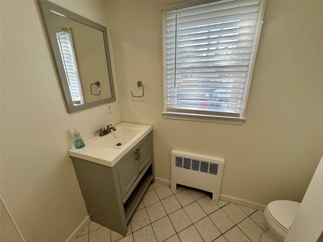 half bathroom featuring tile patterned flooring, toilet, vanity, baseboards, and radiator