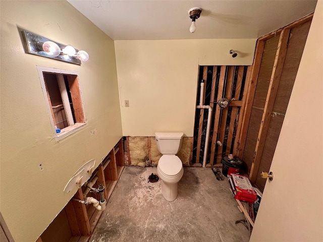 bathroom with unfinished concrete flooring and toilet