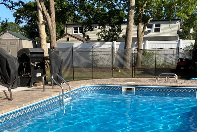 view of swimming pool featuring a fenced in pool, grilling area, a storage unit, fence, and an outdoor structure